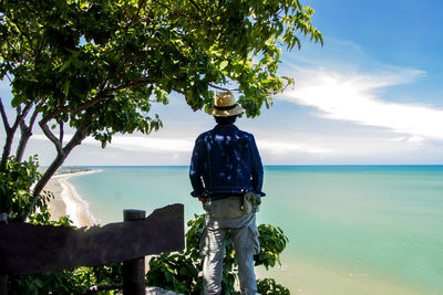 Rear view of mature man standing against sea and sky