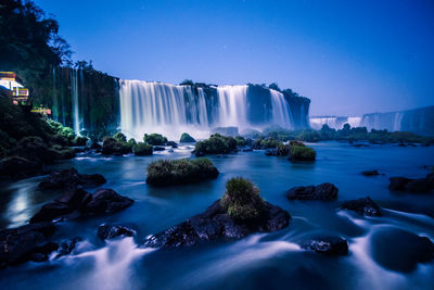Scenic view of waterfall against clear blue sky