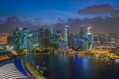 Illuminated city by river against sky at night