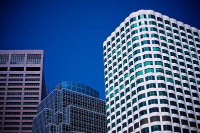Low angle view of modern buildings against clear blue sky