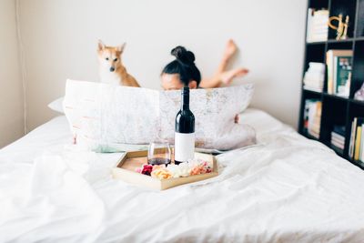 Close-up of woman and dog with drink on bed