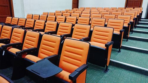 Empty orange chairs in auditorium