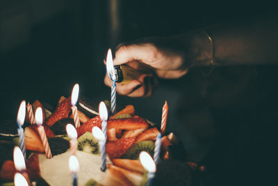 Close-up of woman igniting candles on birthday cake
