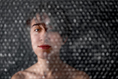 Close-up portrait of a young woman over black background