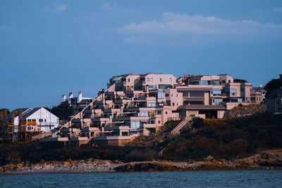 Buildings by sea against sky