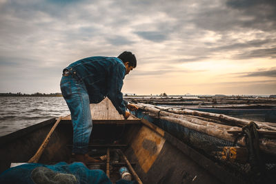 Man standing in boat against sky